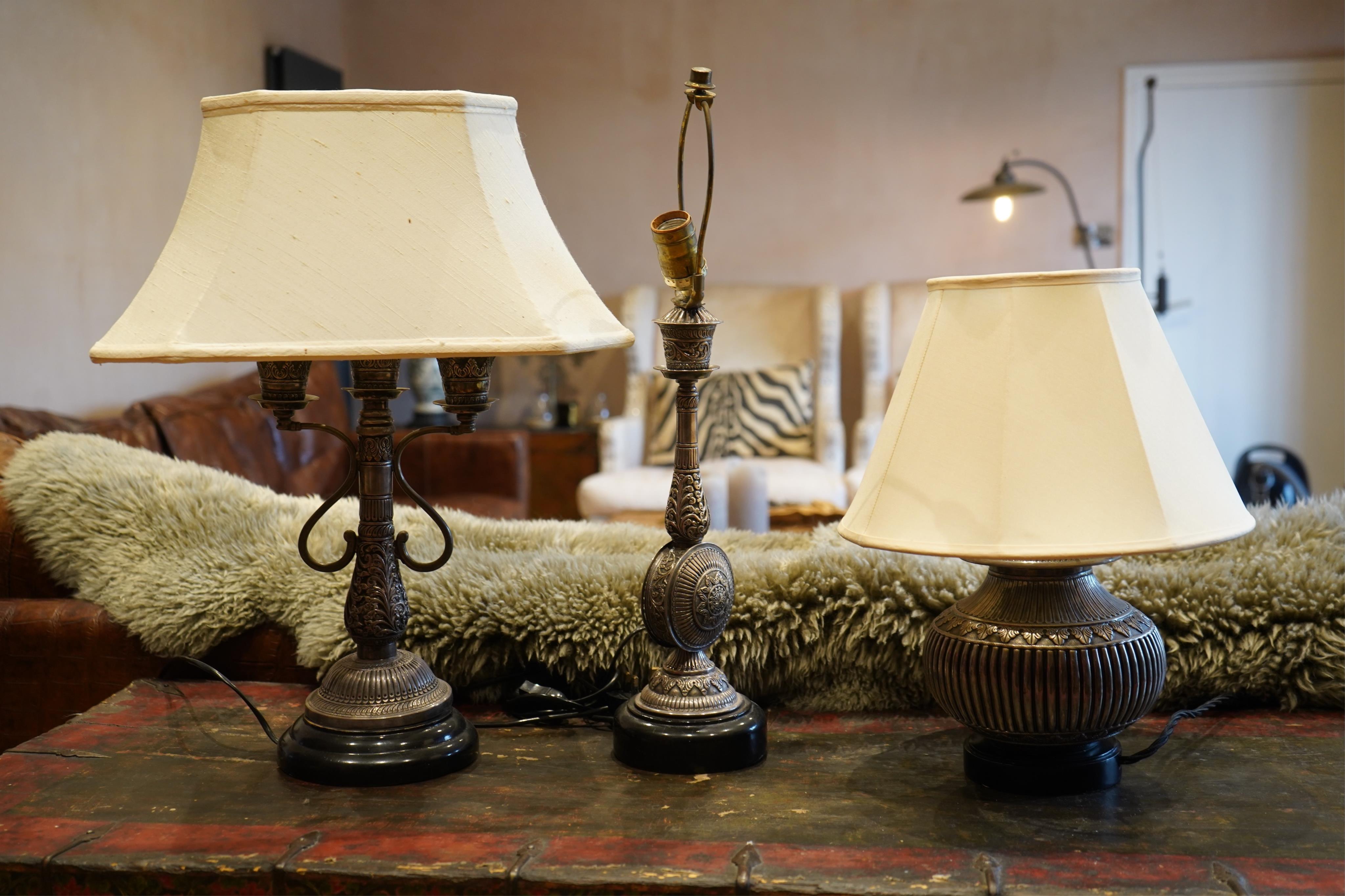 Three early 20th century Indian, Gujarat, silver Kutch Repoussé table lamps, two with shades., largest overall 53cm high. Condition - fair